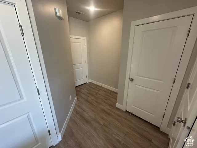 Hallway featuring wood-finish flooring, light neutral wall paint, and white paneled doors
