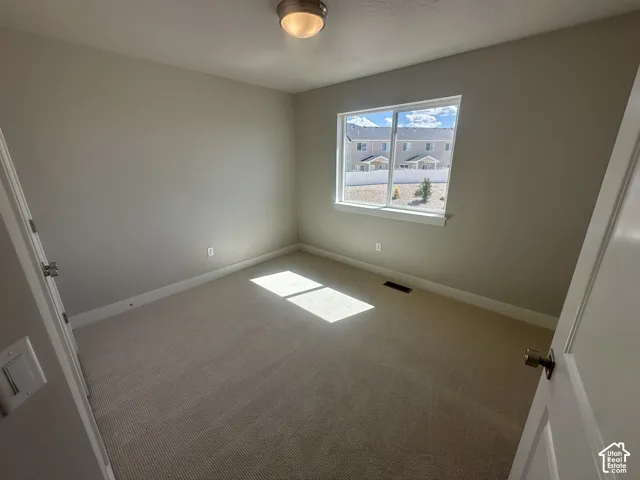 Carpeted room with a double-pane window, neutral painted walls, and a semi-flush mount ceiling light