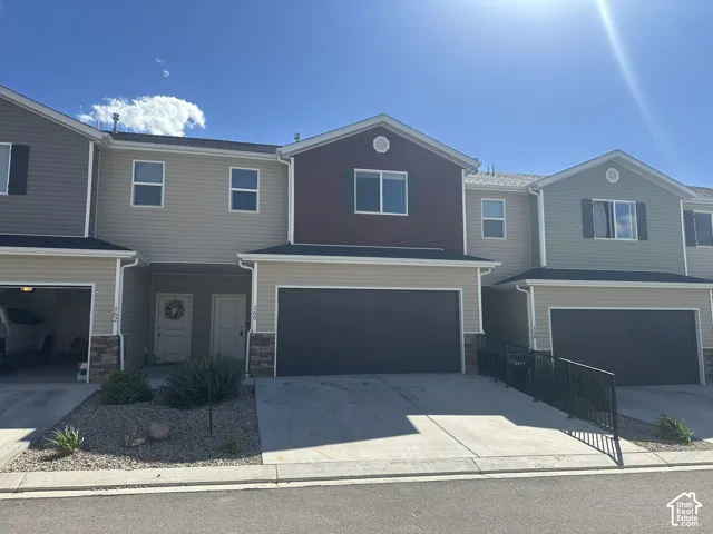 Modern townhome with attached garages, decorative stone veneer accents, and concrete driveways