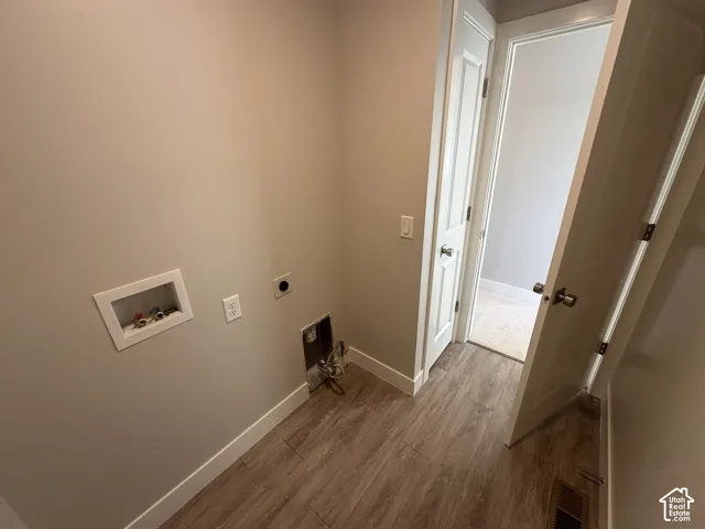 Utility area featuring wood-finish flooring and white trim