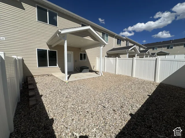 Private outdoor space featuring a covered patio, concrete pad, gravel hardscaping, and full privacy fencing