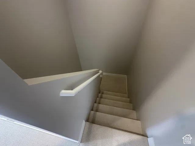 Carpeted staircase with light grey wall paint and white handrail