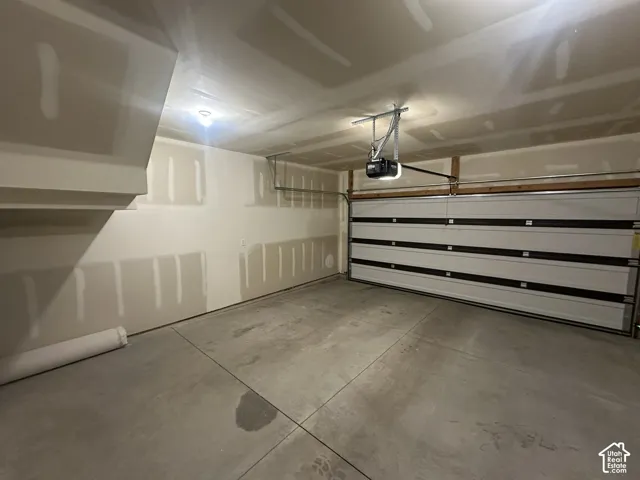 Attached garage with a concrete floor, overhead lighting, and an automatic garage door opener