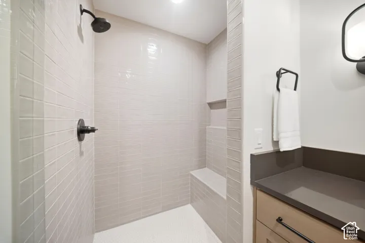 Shower with a built-in bench, tiled walls, and a matte black shower head