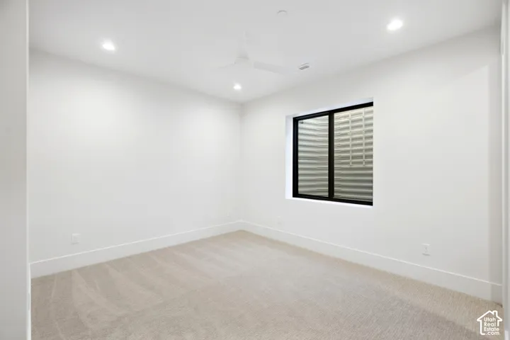 Recessed lighting, ceiling fan, neutral wall paint, carpet flooring, and a black-framed window