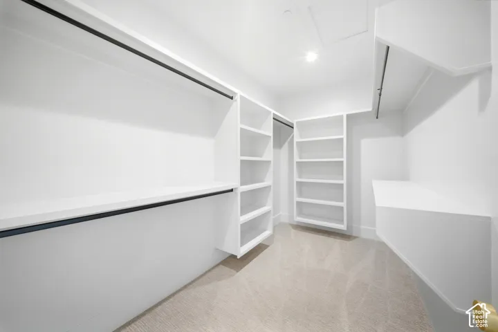 Custom white built-in shelving, multiple hanging rods, and integrated storage compartments