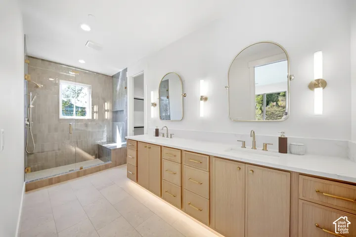 Dual vanities with white countertops, light wood-finish cabinetry, and gold-finish hardware