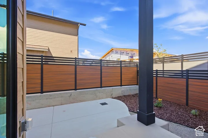 Concrete patio with a wood-finish fence and black metal posts
