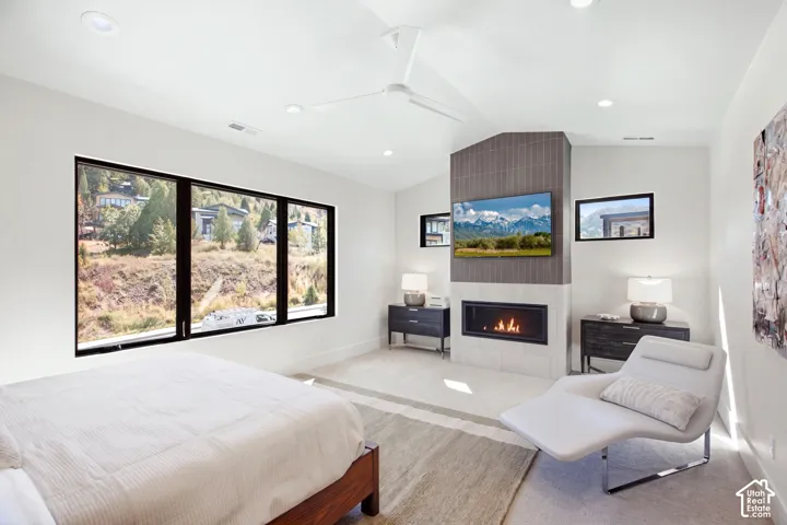Expansive window wall with black framing, contemporary fireplace with a tiled surround, recessed lighting, and a modern ceiling fan