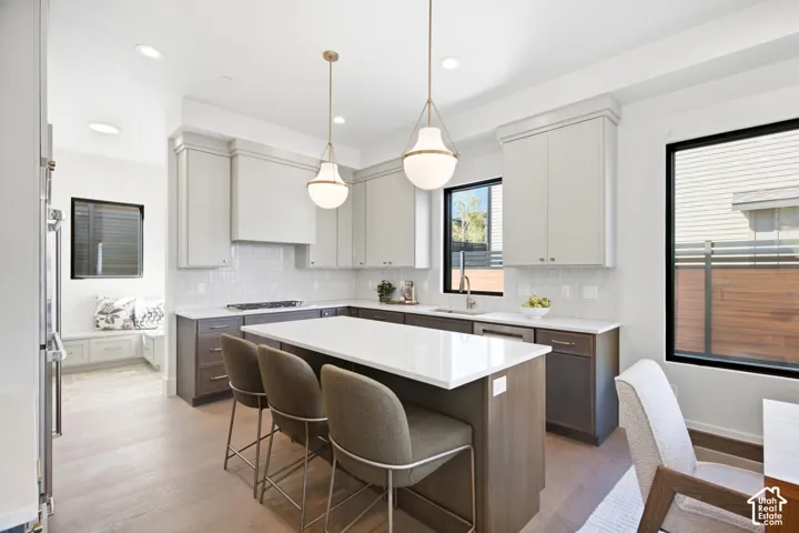 Gourmet kitchen with wood-finish flooring, white countertops, two-tone cabinetry, and a large island with pendant lighting