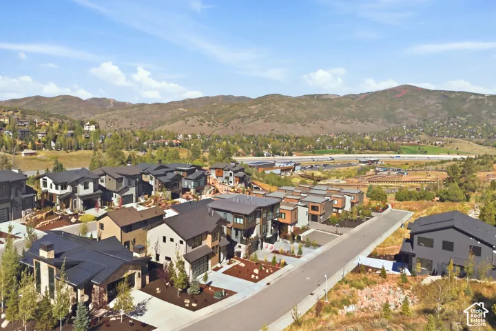 Modern residential community with varied architectural styles, asphalt roadways, and landscaped grounds set against a natural mountain backdrop