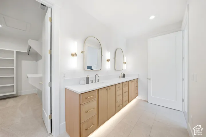 Dual vanity with wood-finish cabinetry, under-cabinet lighting, and white countertops