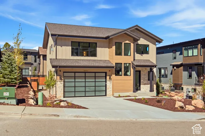 Modern architectural style featuring a multi-tone exterior, stone accents, and a contemporary glass panel garage door