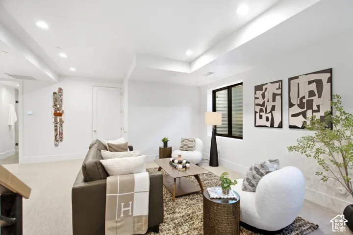 Recessed lighting illuminates a spacious living area featuring light-toned carpeting