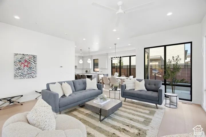Open-concept living area with light wood-finish flooring, recessed lighting, and a contemporary ceiling fan