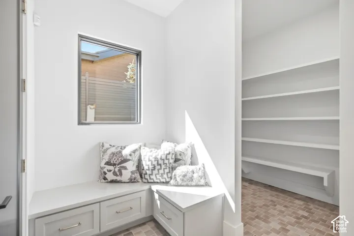 Built-in storage bench with drawers, framed window, light-toned wall paint, integrated shelving, and tile flooring