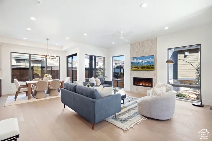 Recessed lighting, wood-finish flooring, a linear fireplace with stone tile surround, and expansive windows