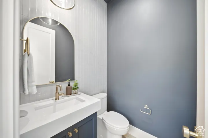 Contemporary vanity with an integrated basin, gold-finish faucet, arched mirror, and vertical tile wall accent