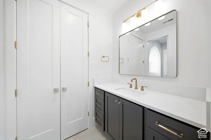 White vanity with integrated sink, gold-finish fixtures, and a rectangular mirror