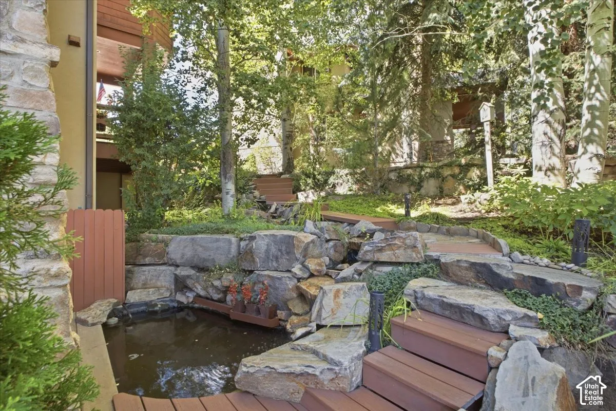 Water feature with natural stone and tiered landscaping, wood-finish decking, and mature trees