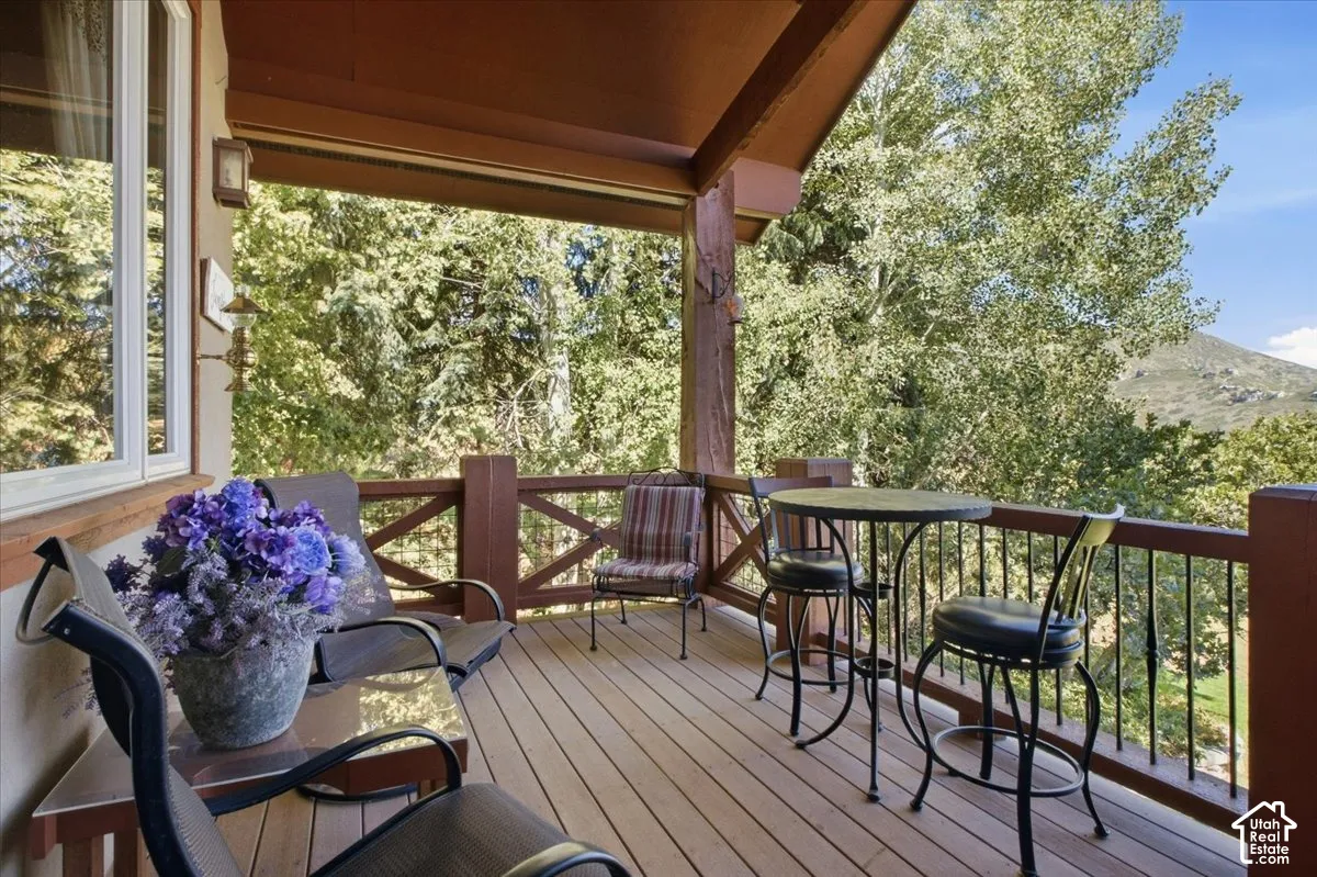 Spacious outdoor deck with wood-finish flooring, wood railings, and a mountain backdrop