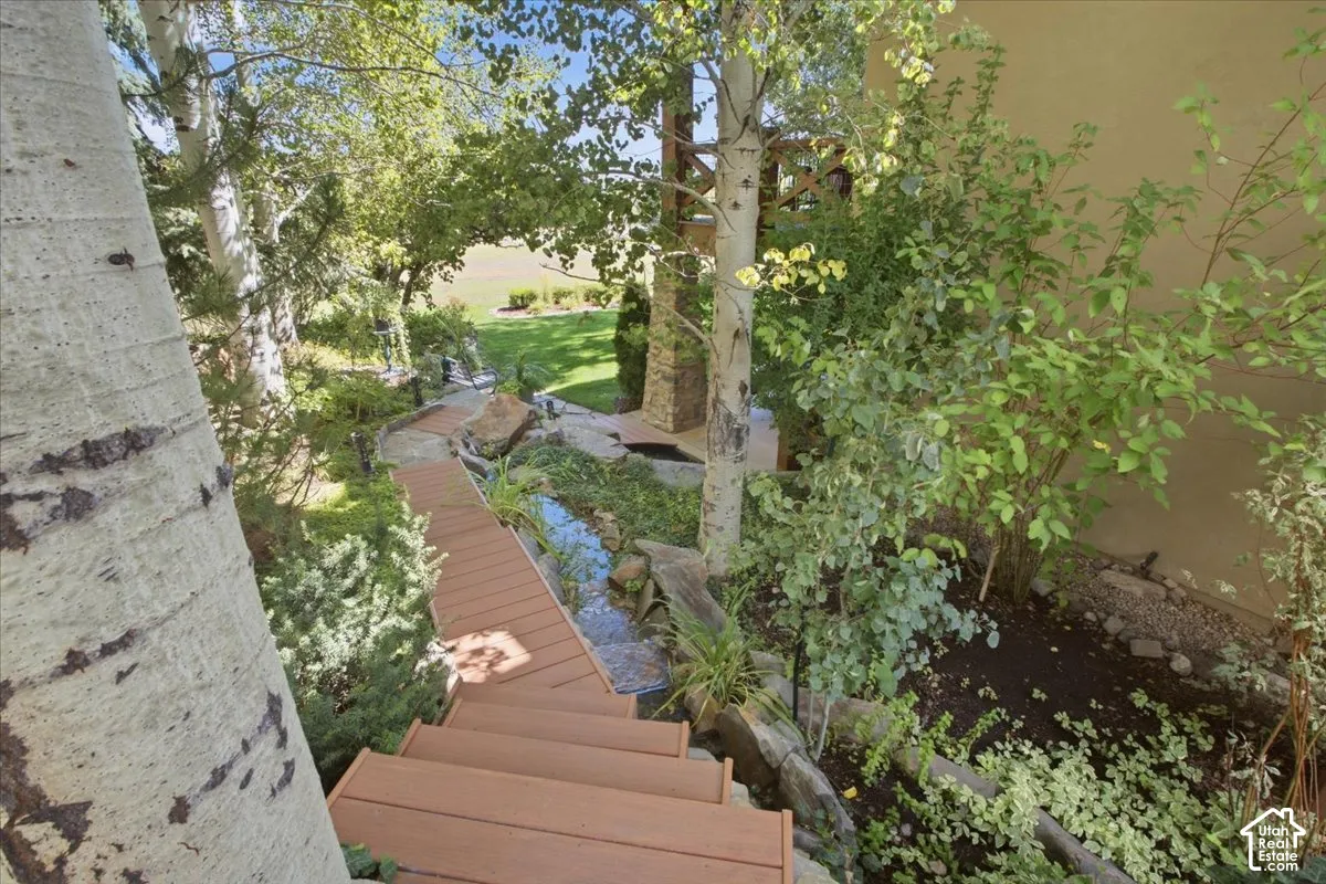 Landscaped outdoor area featuring a wood-finish pathway, stairs, and a water feature