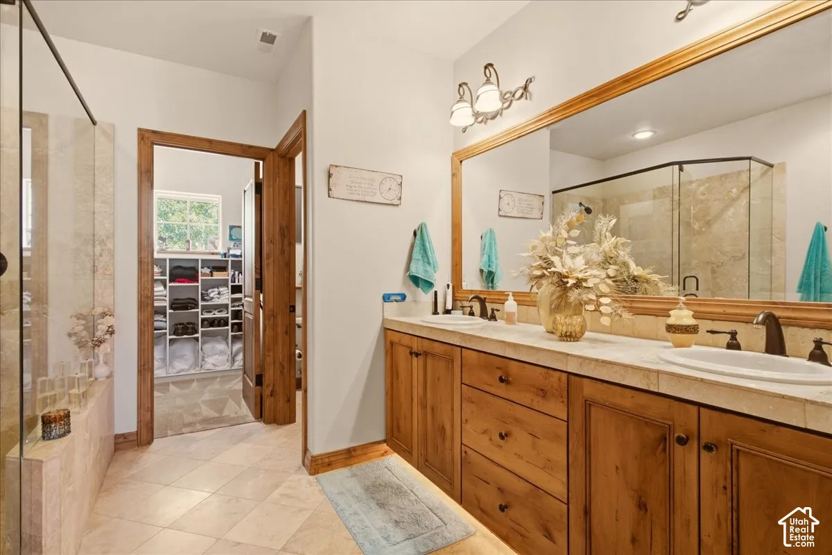 Owner's Bathroom featuring a dual vanity with wood-finish cabinetry, a large framed mirror, and integrated lighting