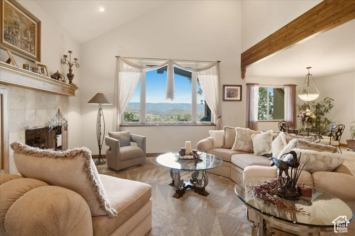Vaulted ceilings with exposed wood beams, fireplace with a mantel, and large windows showcasing the view of the valley