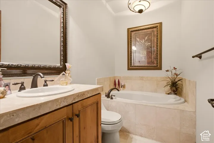 Built-in jetted tub with tile surround, wood-finish vanity with an oval sink, and a framed mirror