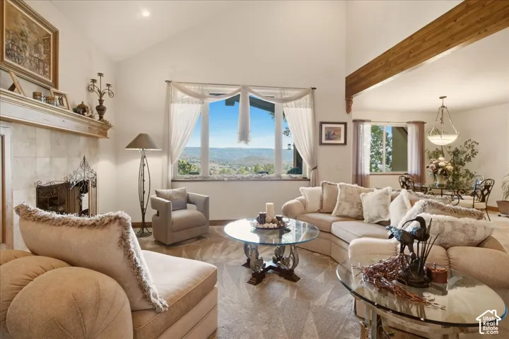 Vaulted ceilings with exposed wood beams, fireplace with a mantel, and large windows showcasing the view of the valley