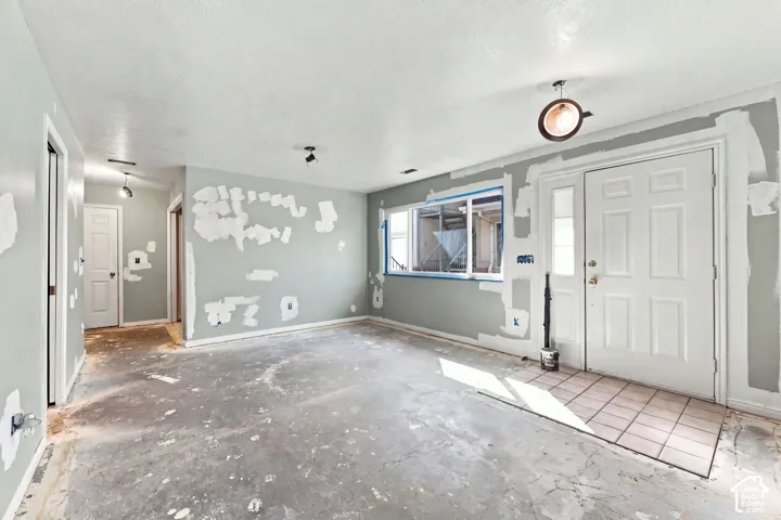 Interior space featuring a white entry door with an adjacent window, recessed lighting, and a tiled entry