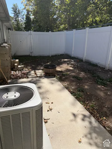 Private backyard space featuring a white vinyl privacy fence and concrete patio