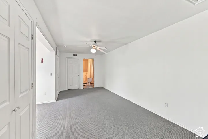 White painted walls, gray carpet flooring, white paneled doors, and a ceiling fan with light fixture