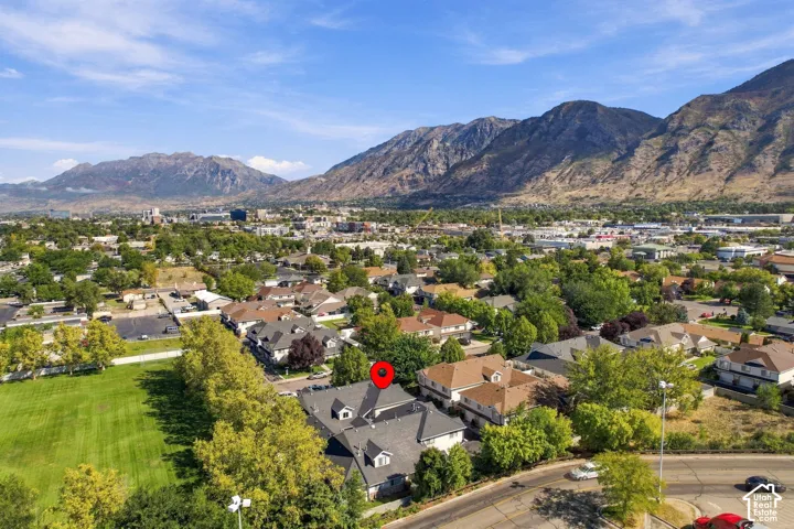 Mountainous backdrop, residential neighborhood, surrounding green spaces, and mature trees
