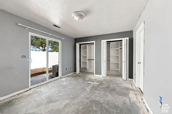 Dual bi-fold door closets, recessed ceiling light fixture, and a sliding glass door providing exterior access