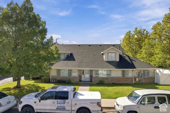 Two-story residential building with a dark shingle roof, light-colored siding, and brick accents