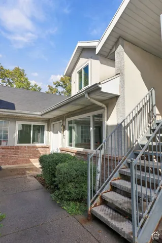 Stucco exterior with brick detailing, multi-pane windows, and a metal staircase with railing