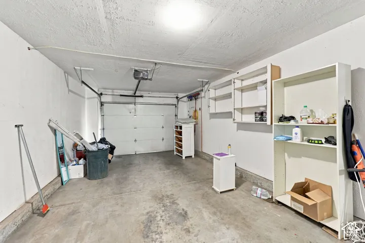 Attached garage featuring an overhead door, built-in shelving, and a concrete floor