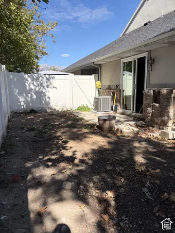 Enclosed backyard featuring a white privacy fence and a rear patio with sliding glass doors