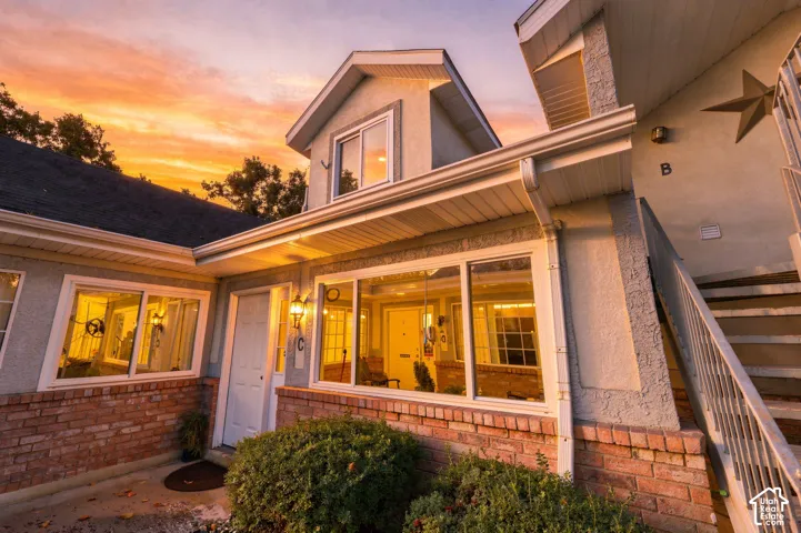 Stucco exterior with brick detailing, white window frames, an outdoor wall sconce, and a second-story dormer
