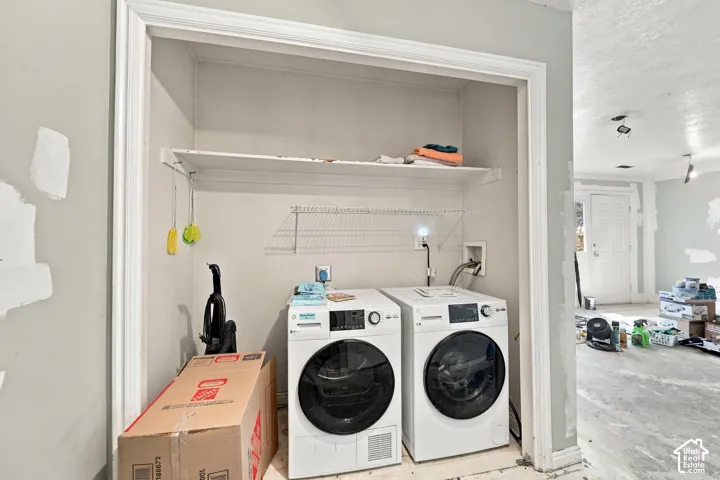 Dedicated laundry area featuring modern white front-load appliances, a built-in shelf, and wire shelving