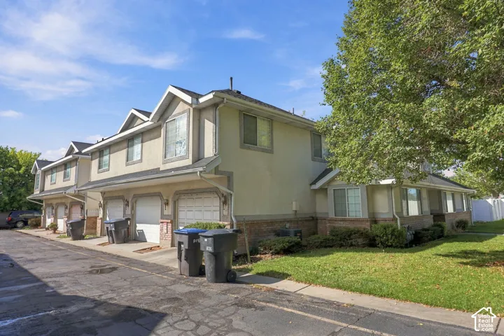 Stucco exterior with brick detailing, attached garages, bay windows, and mature landscaping