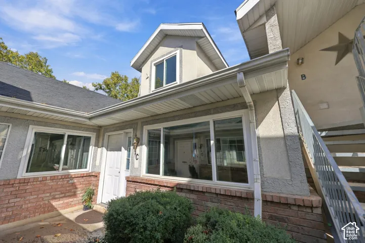 Stucco exterior with brick detailing, multi-pane windows, and a dark shingle roof