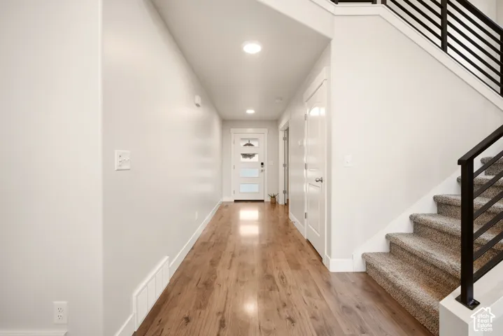 Wood-finish flooring with recessed lighting, white trim, and a contemporary front door