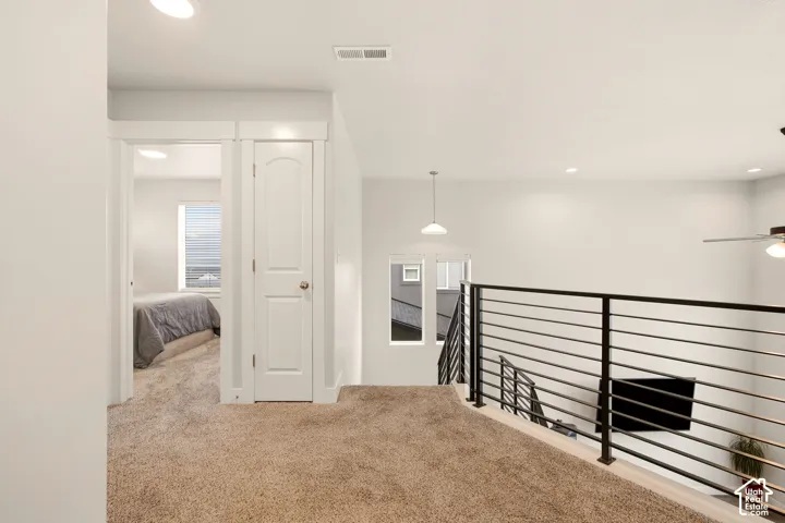Contemporary interior with recessed lighting, carpeted flooring, and a black horizontal rod iron railing