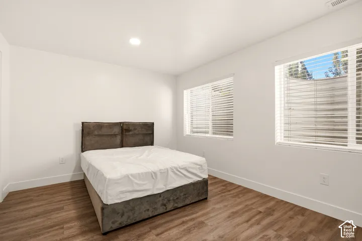 White walls, recessed ceiling lighting, wood-finish flooring, and white window blinds