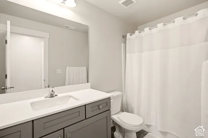 Bathroom featuring a vanity with a white countertop and gray cabinetry, an undermount sink with a chrome faucet, a large wall-mounted mirror, and a shower-tub combination