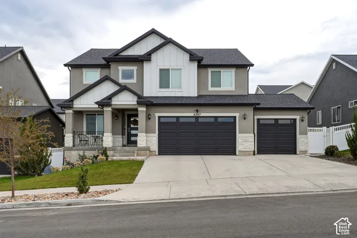 Contemporary stucco exterior with white vertical siding accents, a covered porch, a three-car garage, and a concrete driveway