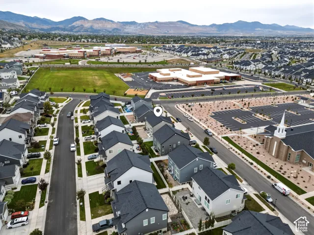 Residential neighborhood with a curved street, adjacent open green space, and distant mountain backdrop