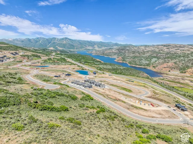 Expansive mountain and lake scenery, featuring multiple community ponds, winding paved roads, and a cluster of contemporary residences